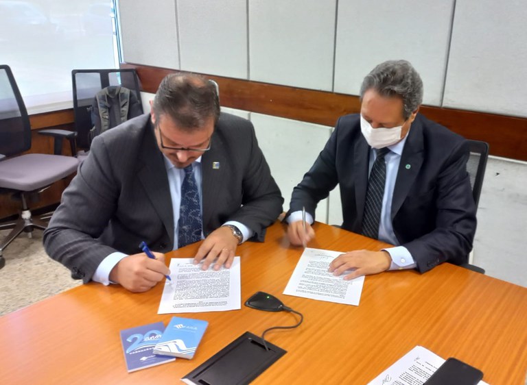 Diretor interino da ANA Luis André Muniz (à dir.) e o diretor do INPE, Clezio De Narin, assinam documentos durante a reunião
