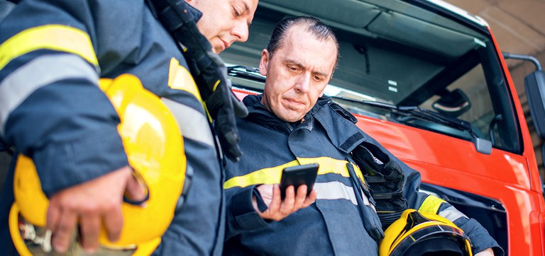 Bombeiros olham para um celular