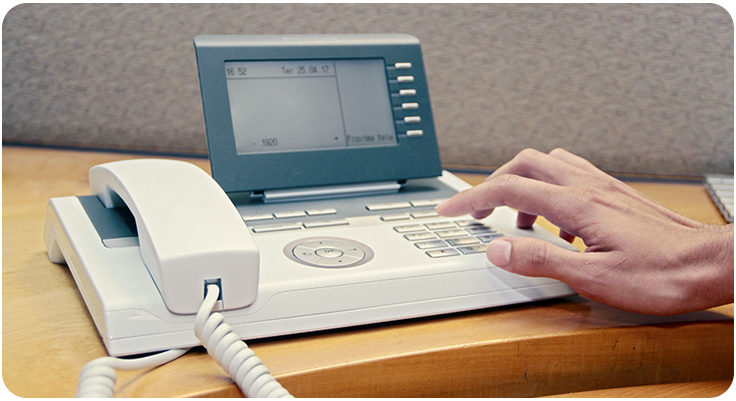 Mão teclando em um telefone fixo