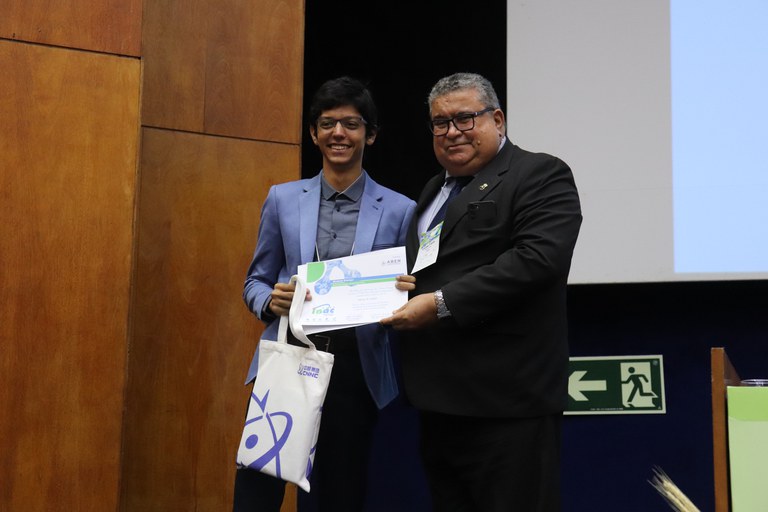 Mateus Chalub recebe o certificado de 1º lugar do Junior Poster INAC 2024 do presidente da Aben, Carlos Freire Moreira (Foto: Deivid Oliveira)
