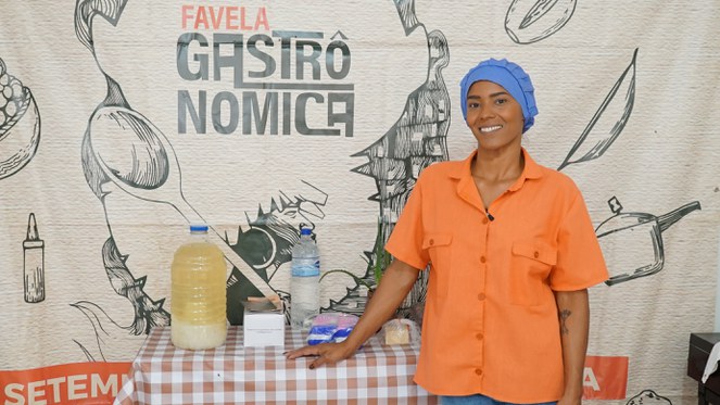 Na foto Cleide Morais da Favela Gastronômica posa ao lado de uma mesa com lanches