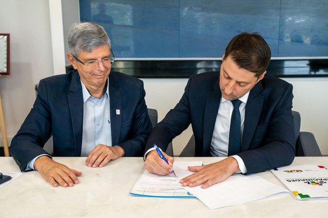 Na foto o Carlos Tomé Junior (à direita), e o reitor Roberto Medronho (à esquerda), assinam o documento da parceria.