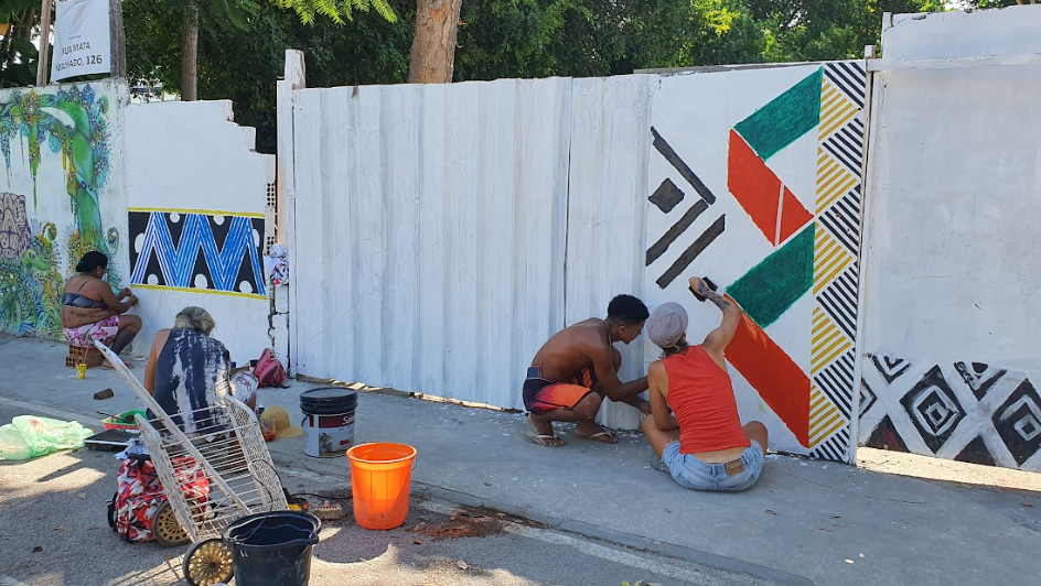 Imagem de pessoas indígenas pintando um muro