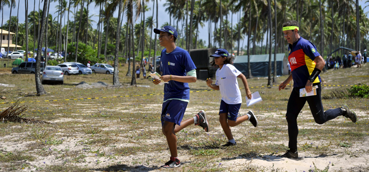 Competidores da modalidade orientação correm na praia de Imbassaí (BA)