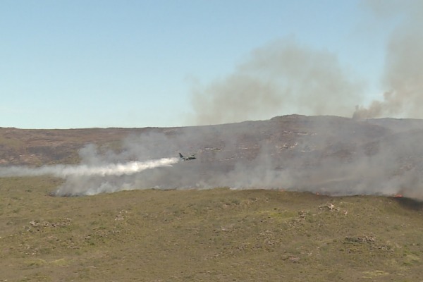 Avião C-130 Hércules lançando água sobre chamas