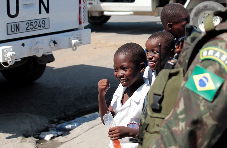 Criança haitiana se prepara para cumprimentar militares brasileiros com um "soquinho", gesto que, na região, simboliza amizade