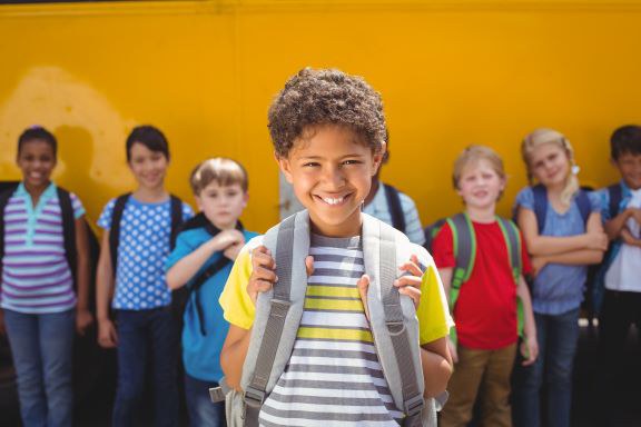 cute-pupils-smiling-camera-by-school-bus.jpg