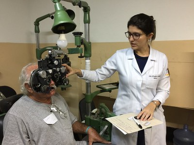 Médica realiza exame de refração em paciente idoso