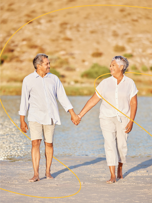 Casal de idosos de mãos dadas na praia.