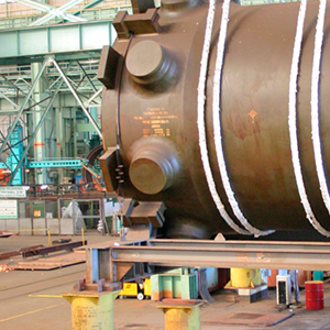 Imagem da galeria de imagem da página Nuclear. A imagem mostra um grande equipamento sendo manuseado dentro de uma fábrica. Todo o cenário ao fundo é da fábrica.