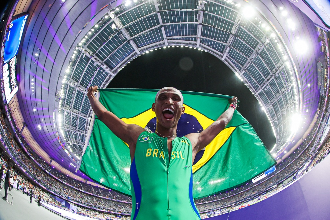 Alison dos Santos com a bandeira brasileira após a conquista do bronze nos 400m com barreira. Foto: Wander Roberto/COB