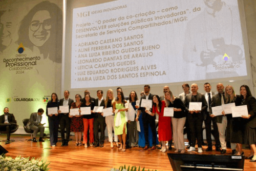 Imagem de um grupo de premiados no palco com seus certificados, pousando para as fotos.