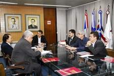 Várias pessoas sentadas ao redor de uma mesa conversando entre si.