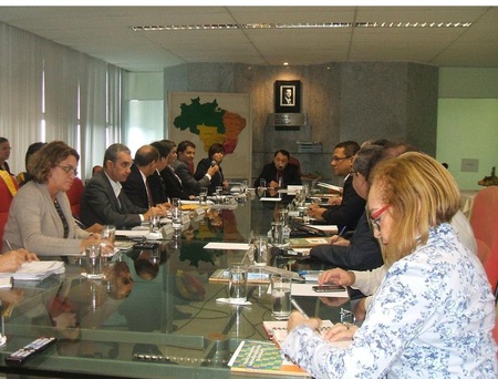 Várias pessoas sentadas ao redor de uma mesa e conversando entre si.