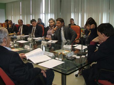 Várias pessoas sentadas ao redor de uma mesa e conversando entre si.