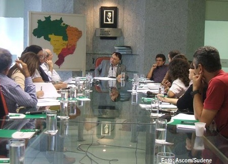 Várias pessoas sentadas ao redor de uma mesa e conversando entre si.