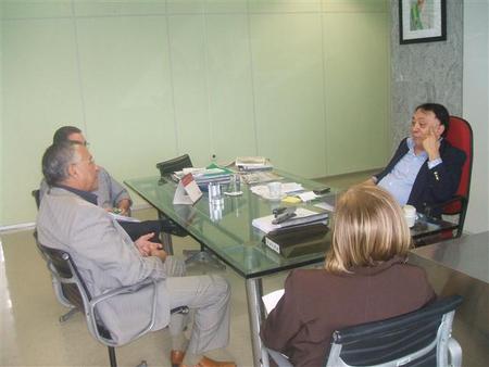 Superintendente da Sudene Paes Landim sentado commais três pessoas numa mesa. Eles estão conversando entre si.