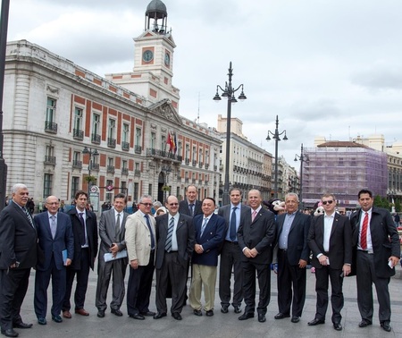 Várias pessoas de pé pousando para uma foto. E um prédio histórico espanhol no fundo.