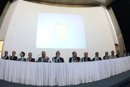 Bancada com várias pessoas sentadas e um datashow de fundo.