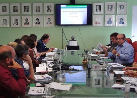 Várias pessoas sentadas ao redor de uma mesa conversando entre si.