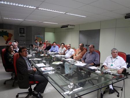 Várias pessoas sentadas ao redor de uma mesa conversando entre si.