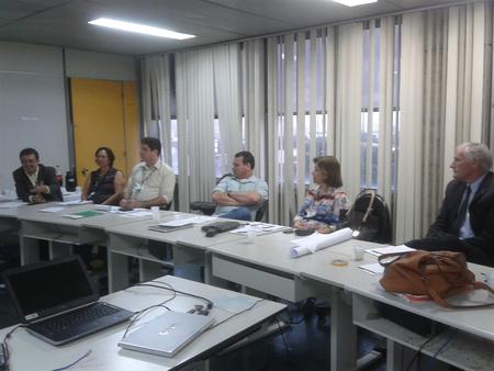 Várias pessoas sentadas ao redor de uma mesa e conversando entre si.