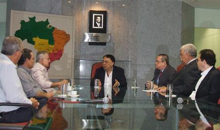 Várias pessoas sentadas ao redor de uma mesa e conversando entre si.