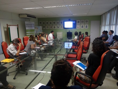 Várias pessoas sentadas ao redor de uma mesa e conversando entre si.