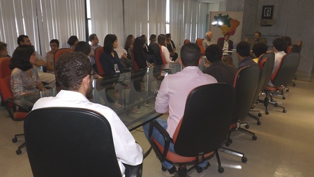 Várias pessoas sentadas ao redor de uma mesa.