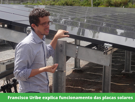 Francisco Uribe com a mão sobre uma placa solar enquanto fala.