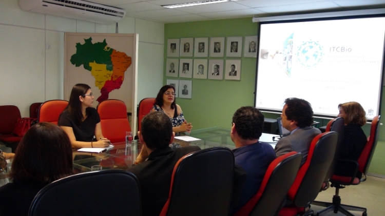 Reunião de representantes do ITCBio com representantes da Sudene. Todos estão sentados em volta de uma mesa de vidro em uma sala, com projetor.