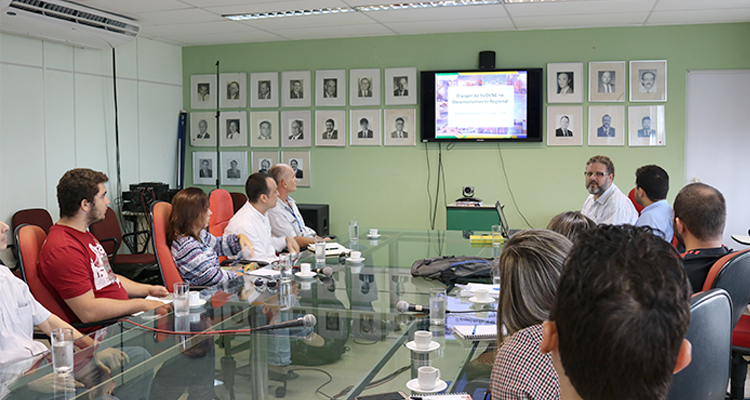 Foto de audiência entre servidores da Sudene e alunos e pesquisadores da Universidade Federal da Paraíba. Todos estão sentados em cadeiras ao redor de uma mesa de uma sala de reuniões.