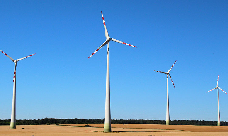 Foto de aerogeradores (em um total de quatro) com um céu bem azul (compatível com um dia ensolarado ao fundo