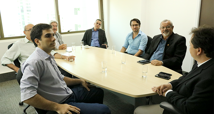 Foto de uma mesa de reunião com sete pessoas sentadas.