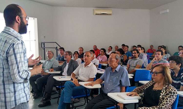 A foto mostra o palestrante em primeiro plano e a plateia (todos sentados) durante o workshop.