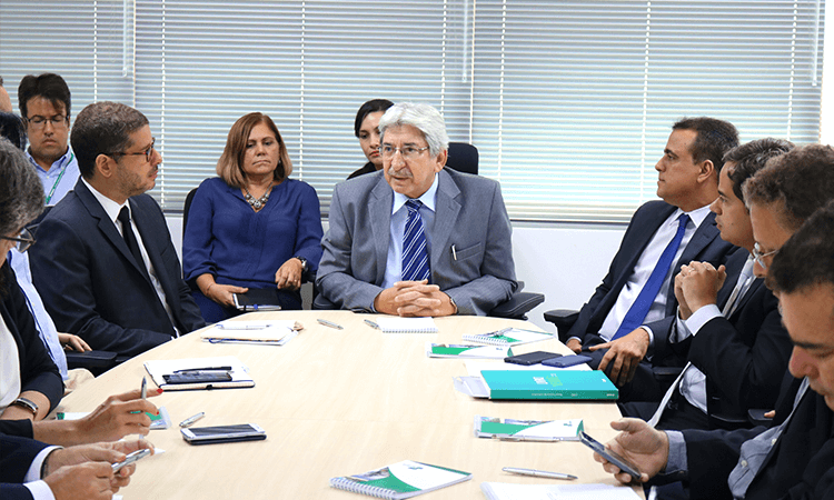 Foto de pessoas ao redor de uma mesa durante uma reunião.