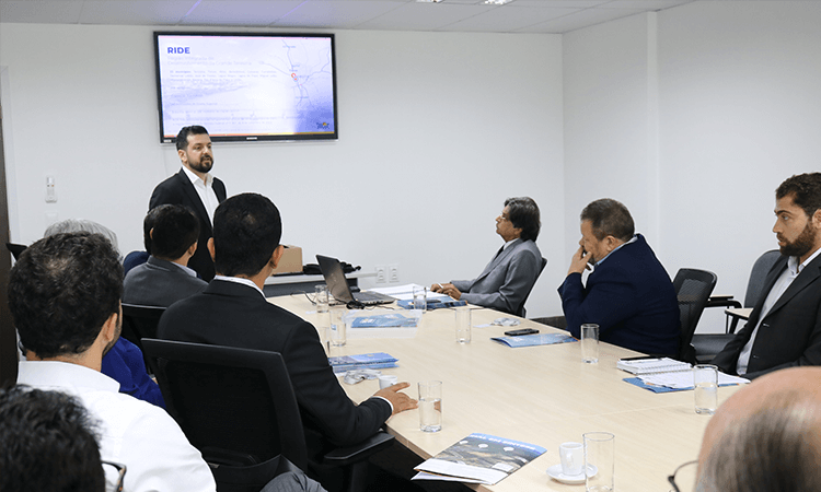 Foto de pessoas ao redor de uma mesa durante uma reunião.