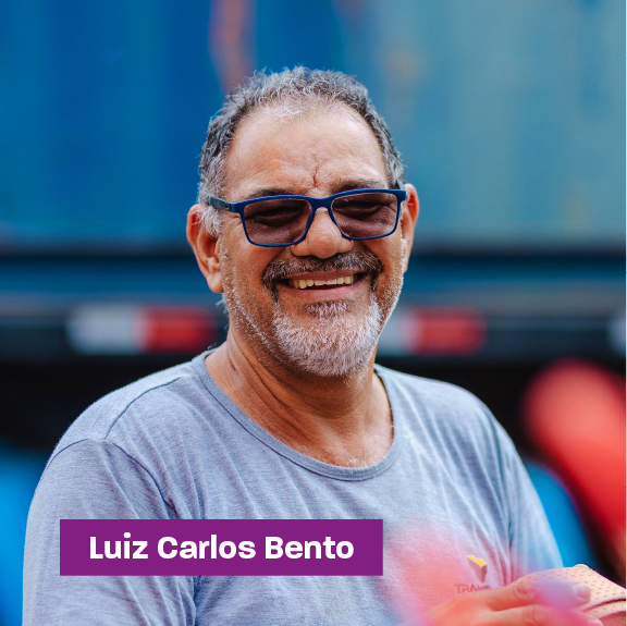 Foto de Luiz Carlos Bento sorrindo na frente de um caminhão azul com blusa cinza